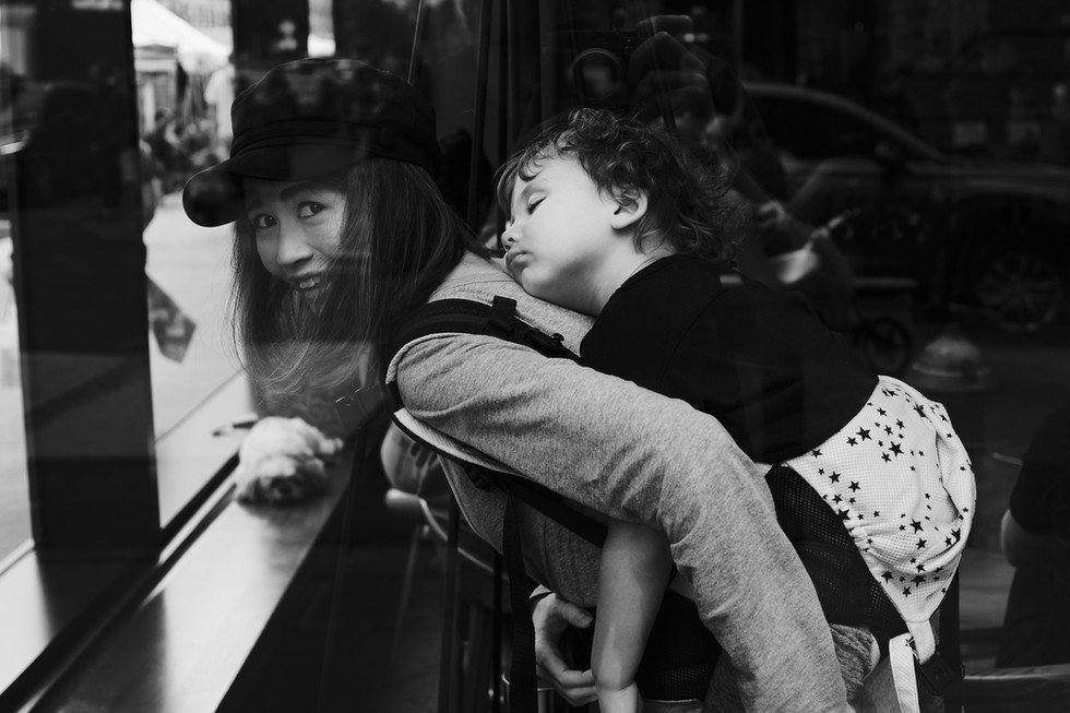 Usmívající se žena se svým spícím dítětem na zádech