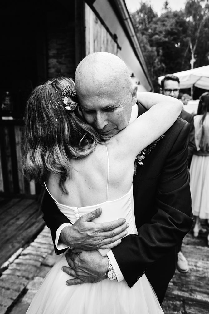 Otec objímá nevěstu při svatebních gratulacích