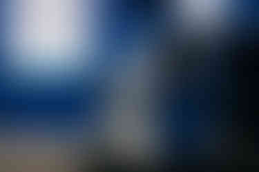 Muž se dívá do objektivu skrz okénko zaparkovaného auta