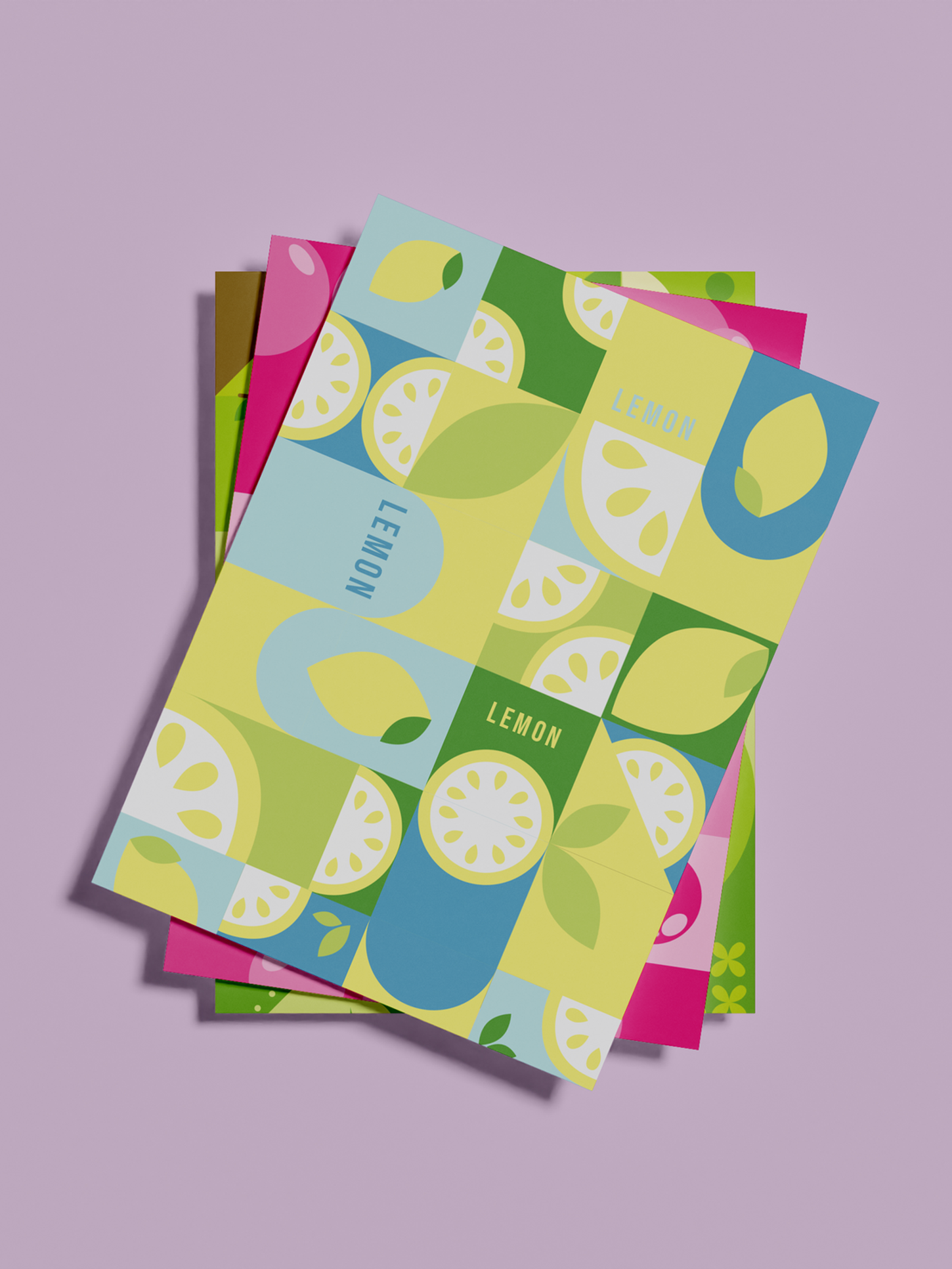 A stack of posters with the top one being yellow, featuring geometric art of lemons. The second poster has a pink bubblegum design, and the bottom poster showcases a green apple design.