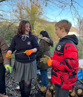 Two young children volunteering in a garden and smiling together