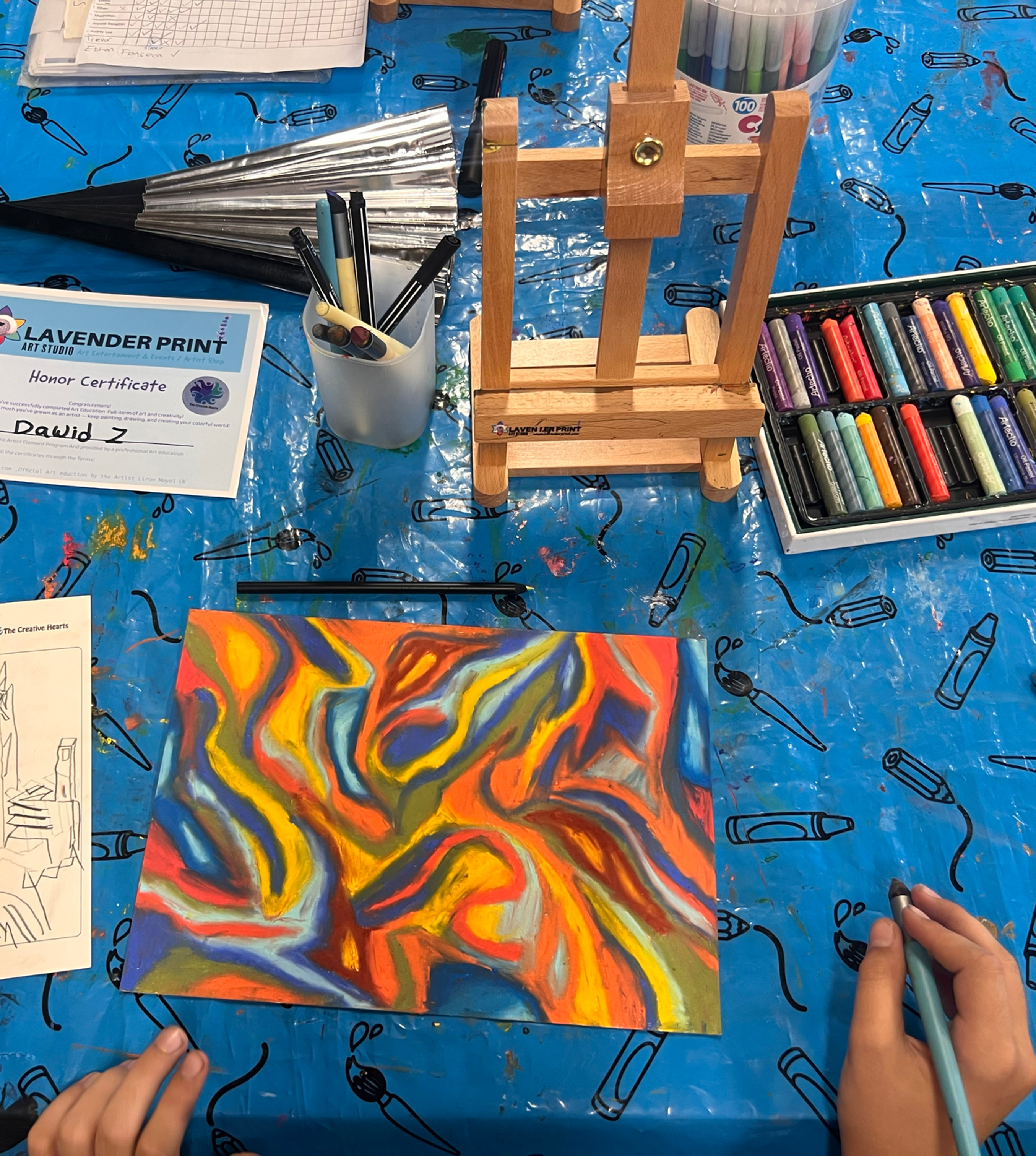 Eye-level view of a child shaping clay at a table with paint marks and craft materials nearby