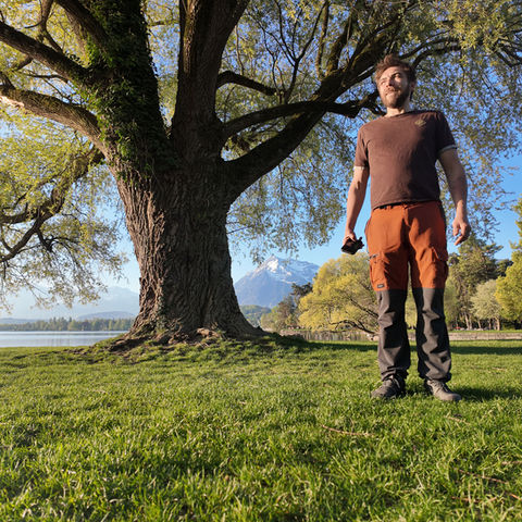 Man standing in a park next to a large tree
