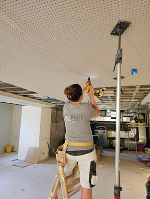 Handwerker montiert Deckenplatten mit einem Stuetzer.