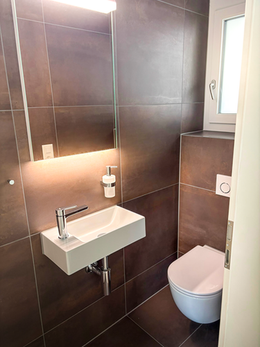 Modernes Gäste-WC mit Wandwaschbecken und WC-Anlage.