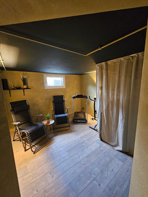 Wellnessraum mit Liegen, Vorhang und warmem Licht.