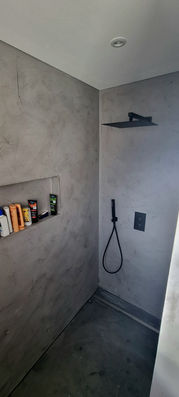 Begehbare Dusche mit Nischen und dunklen Fliesen.