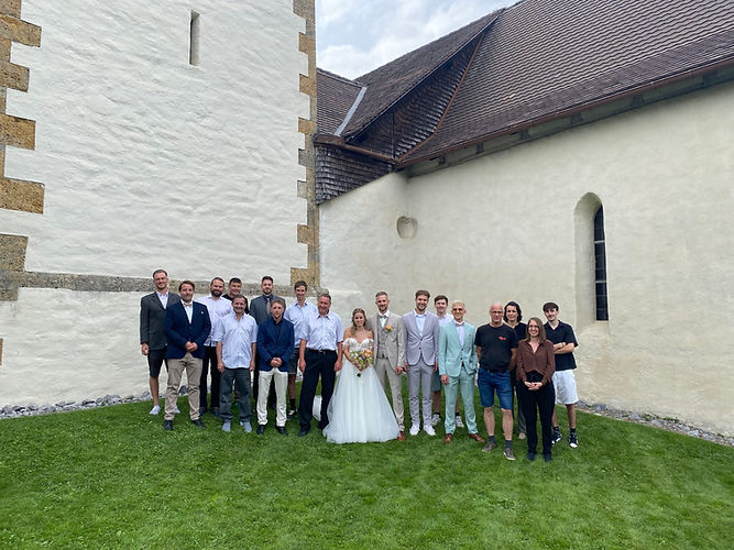 Brautpaar und Gäste vor einer Kirche