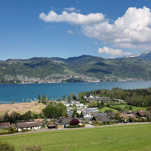 Scenic view of a lakeside town with mountains and clouds.