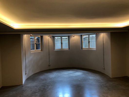 Grosser Raum mit abgerundeter Wand und indirekter Beleuchtung.