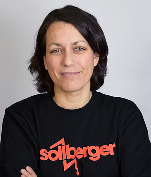 Frau mit dunklem Haar und schwarzem Söllberger-Pullover, Arme gekreuzt