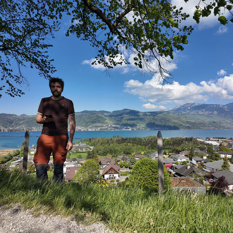 Man overlooking a scenic lake and mountain landscape.