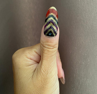 Thumb with chevron patterned nail art design showing good quality affordable nail polishes