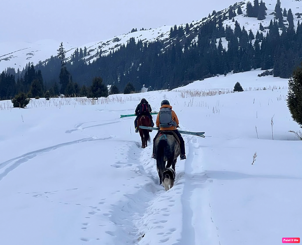 Landscape photo of two people on horseback riding through snowy mountains
