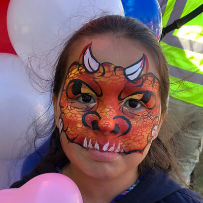 dragon face painting on a girl at a festival fair