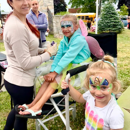 a professional face painter painting fairy faces at a local fair and festival