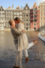 A man holding a woman on the riverbank in couples photoshoot in Amsterdam