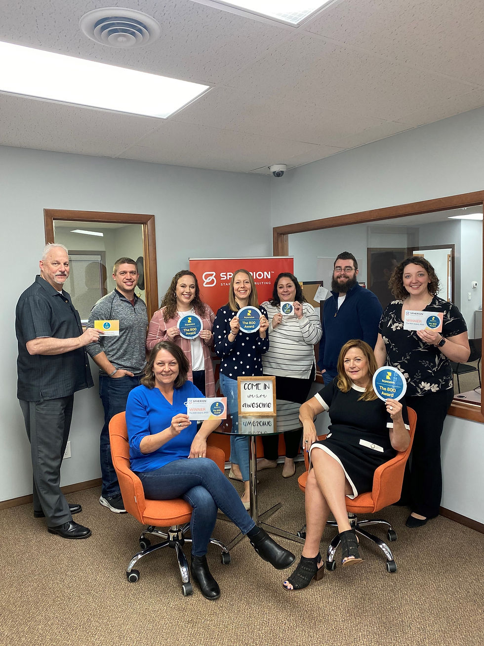 Group of people holding awards in office, Spherion. Staff smiling and posing for photo.