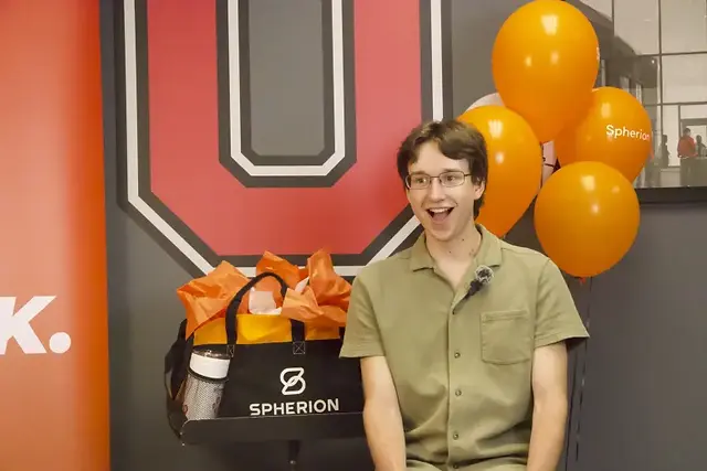 Excited man in front of balloons and Spherion bag. Spherion logo visible.