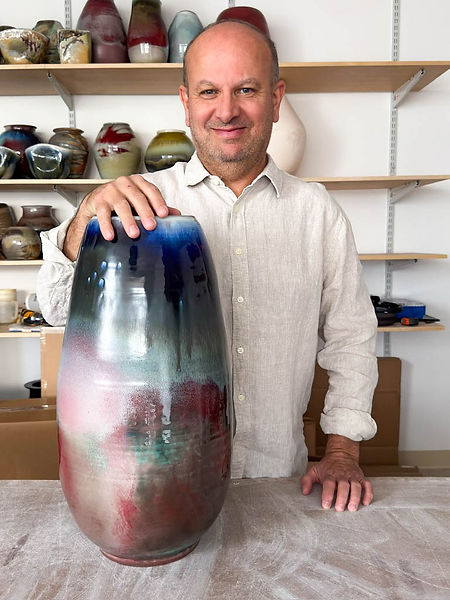 Ceramic artist Jeff Amato standing beside one of his larger soda-fired vases inside his studio in NYC