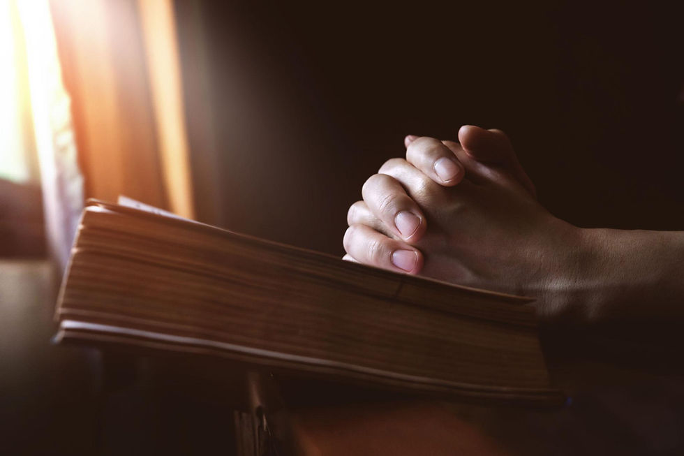 manos orando sobre una Biblia