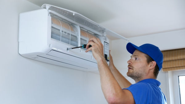 Technician in blue uniform repairing an air conditioner