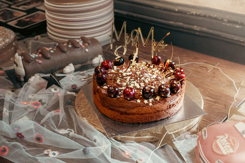 a chocolate cake with cherries and a mr. and mrs. cake topper