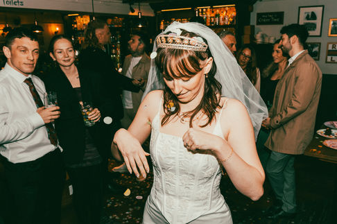 a woman in a wedding dress is dancing in front of a sign that says cake time