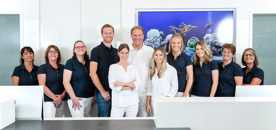 Team der kieferorthopädischen Fachpraxis im hellen Eingangsbereich der Praxis