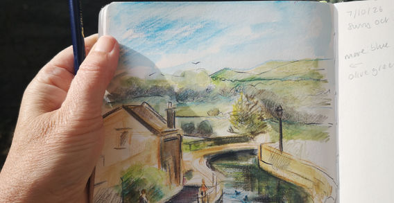 Open sketchbook with a sketch of Kildwick canal created with Derwent inktense pencils
