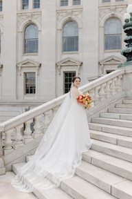Bride with cathedral veil and red, pink and yellow bright floral bouquet photographed portrait on the steps of the Wisconsin State Capitol just two blocks from at The Madison Club, a Madison Wisconsin Wedding Venue