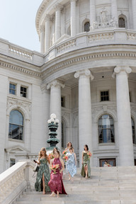 Bridesmaids in mismatched colors walking down the Wisconsin State Capitol steps outdoor at The Madison Club, a Madison Wisconsin Wedding Venue
