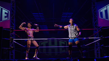 Wrestler pointing at another wrestler who is flexing