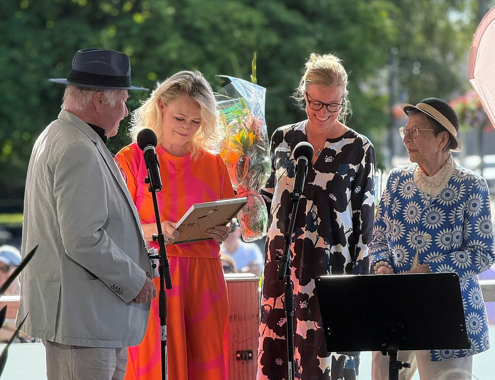 Helsingin Savonlinna-seuran puheenjohtaja Pekka Anttonen (vas.) palkitsemassa uutta Mustaa Pässiä, taiteilija Johanna Orasta. Palkintoa luovuttamassa myös seuran varapuheenjohtaja Anu Kuutti ja seuran kunniapuheenjohtaja Sirkka-Liisa Hentilä.