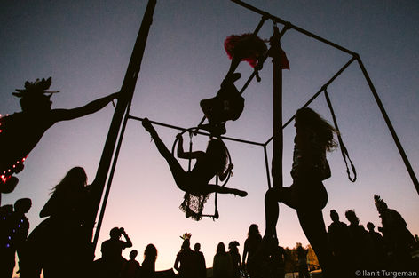 אנשים משחקים על נדנדות, סילואטים על רקע שקיעה, תמונה מאת באנית טונגמן.