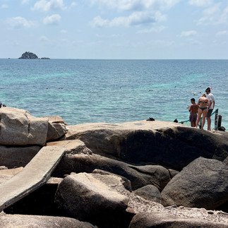 חוף סלעי בקו טאו עם מים צלולים ומשפחה