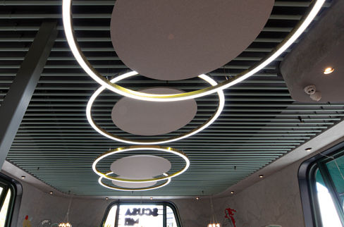 Suspended circular acoustic panels with gold ring lights installed by BACH Commercial at Scusa Mi Italiano restaurant.