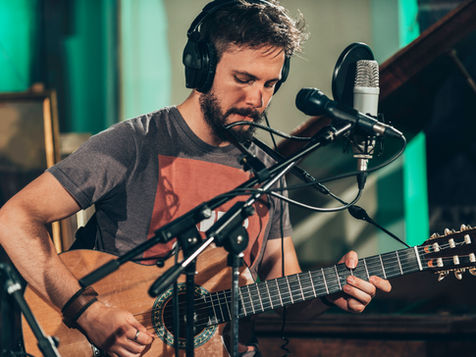 caucasian male playing an acoustic guitar and singing