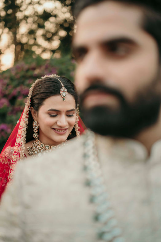 Smiling Purna in red veil behind Abhishek