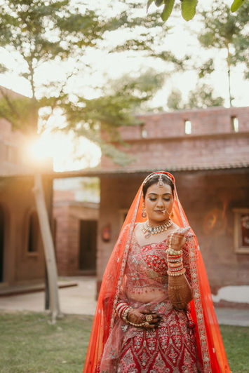 Akanksha, a bride in red traditional attire outdoors