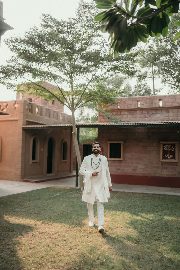 Aditya in white traditional attire walks in a courtyard