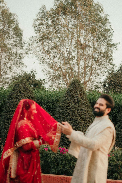 Purna in red veil and Abhishek smiling, holding hands