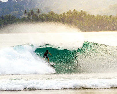Surfer riding a wave in the clear waters of Mentawai Islands