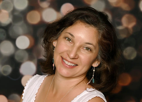 Woman smiling with dark shoulder length hair in a white top