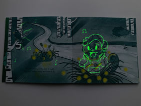 A chameleon child stands on a riverbank, surrounded by fireflies but looking indifferent. A blackbird perches on a nearby tree.
Under black light a hidden image becomes visible of the chameleon transformed. A boy is gasping at the beauty of the fireflies as insects are his special interest. Musical notes eminate from the blackbird as it's song encourages this unmasked joy.