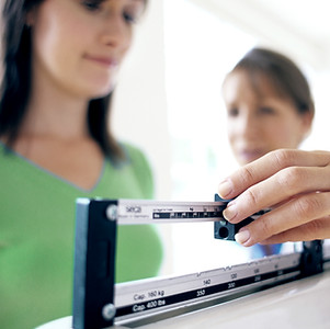 Doctor adjusting balance on weighing scale