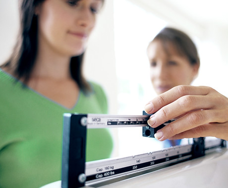 Doctor adjusting balance on weighing scale