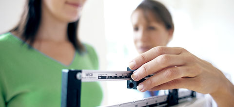 Doctor adjusting balance on weighing scale