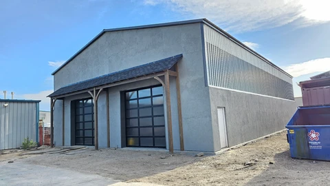 Large gray metal building with two glazed overhead doors and a timber awning