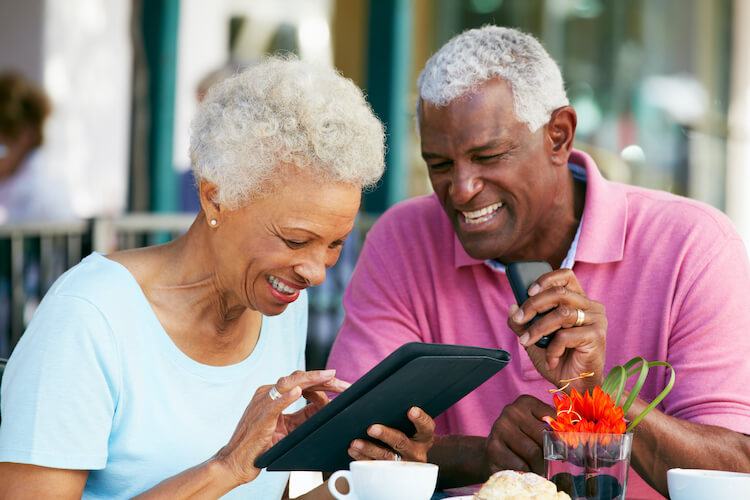 An older couple reviewing something together on a tablet at a cafe